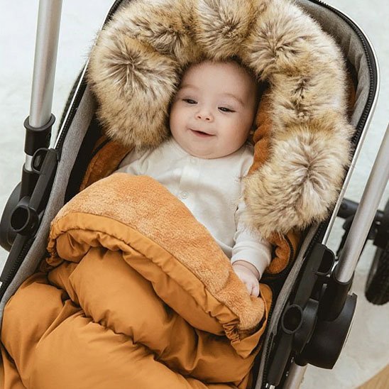 bébé installé sa Chancelière poussette marron installé su une poussette