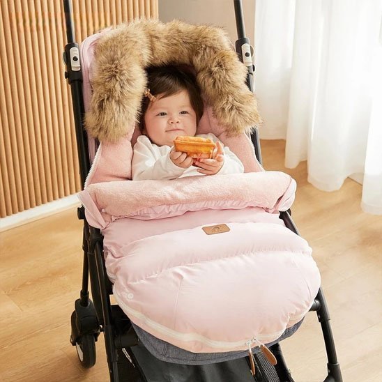 bébé installé sa Chancelière poussette rose installé su une poussette